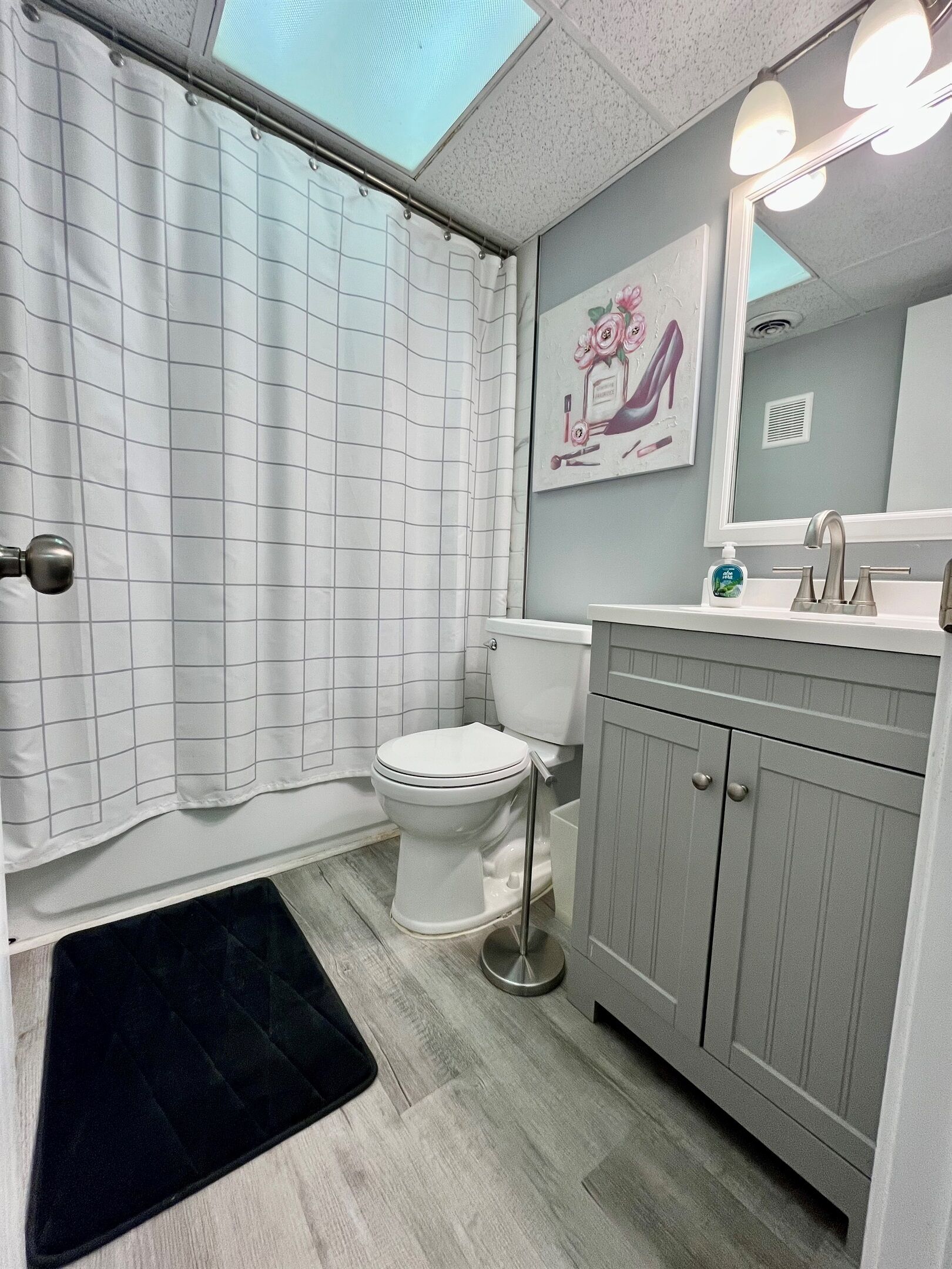 Un baño con inodoro, lavamanos, espejo y cortina de ducha.