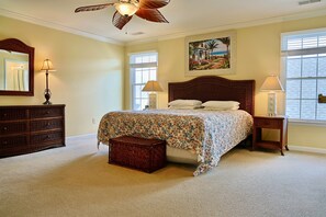 A bedroom with a bed, a dresser, a nightstand, a lamp, a ceiling fan, and a painting on the wall. - XL Resort Beach Home with Pools, Gym, Tennis (Berlin)
