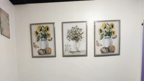 A bedroom with a bed, pillows, a colorful blanket, and three framed artworks on the wall. - 1_Las Asturias Charming Condo Just Steps from Enchanted Kingdom (CITY OF SANTA ROSA)