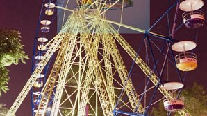 A large Ferris wheel with multiple cabins, a prominent central structure, and a dark sky background. - 1_Las Asturias Charming Condo Just Steps from Enchanted Kingdom (CITY OF SANTA ROSA)