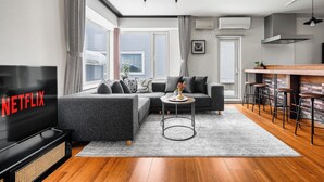 A modern living room with a sectional sofa, a TV, a coffee table, and a bar area with stools. - THE VELVET (Asahikawa)