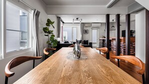 A dining area with a wooden table, chairs, a vase, and a view into the living room. - THE VELVET (Asahikawa)