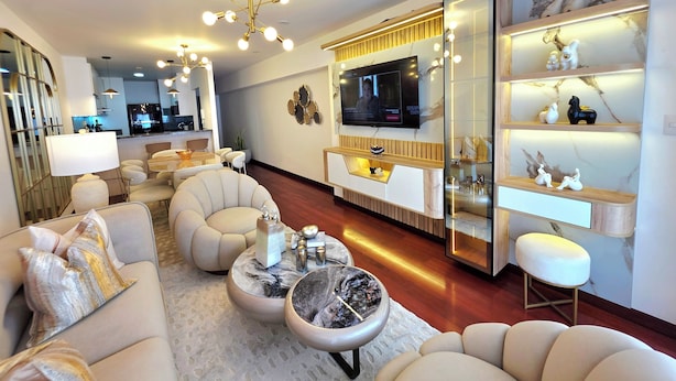 Een moderne woonkamer met een televisie, comfortabele zitplaatsen, een bijzettafeltje en een decoratieve spiegel.