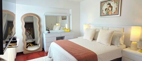 Une chambre à coucher moderne, avec un lit, des tables de chevet, une chaise, un grand miroir et un luminaire au plafond.