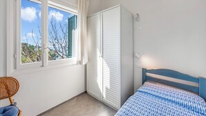 Una camera da letto con un letto, una finestra con persiane, un armadio e una sedia.