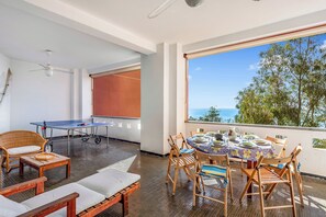 Ein Zimmer mit Tischtennisplatte, Esstisch mit Stühlen, einer Couch und einem großen Fenster mit Blick.