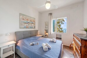 Ein Schlafzimmer mit Bett, Schreibtisch, Kommode, Deckenventilator und Fenster mit Blick.