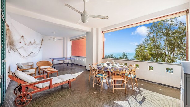 Una stanza con vista, un ventilatore a soffitto, un tavolo con sedie e un divano.