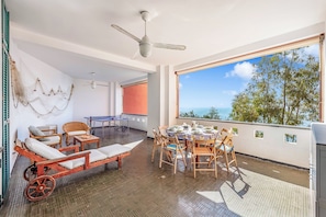 Une pièce avec vue, un ventilateur de plafond, une table avec des chaises et un canapé.