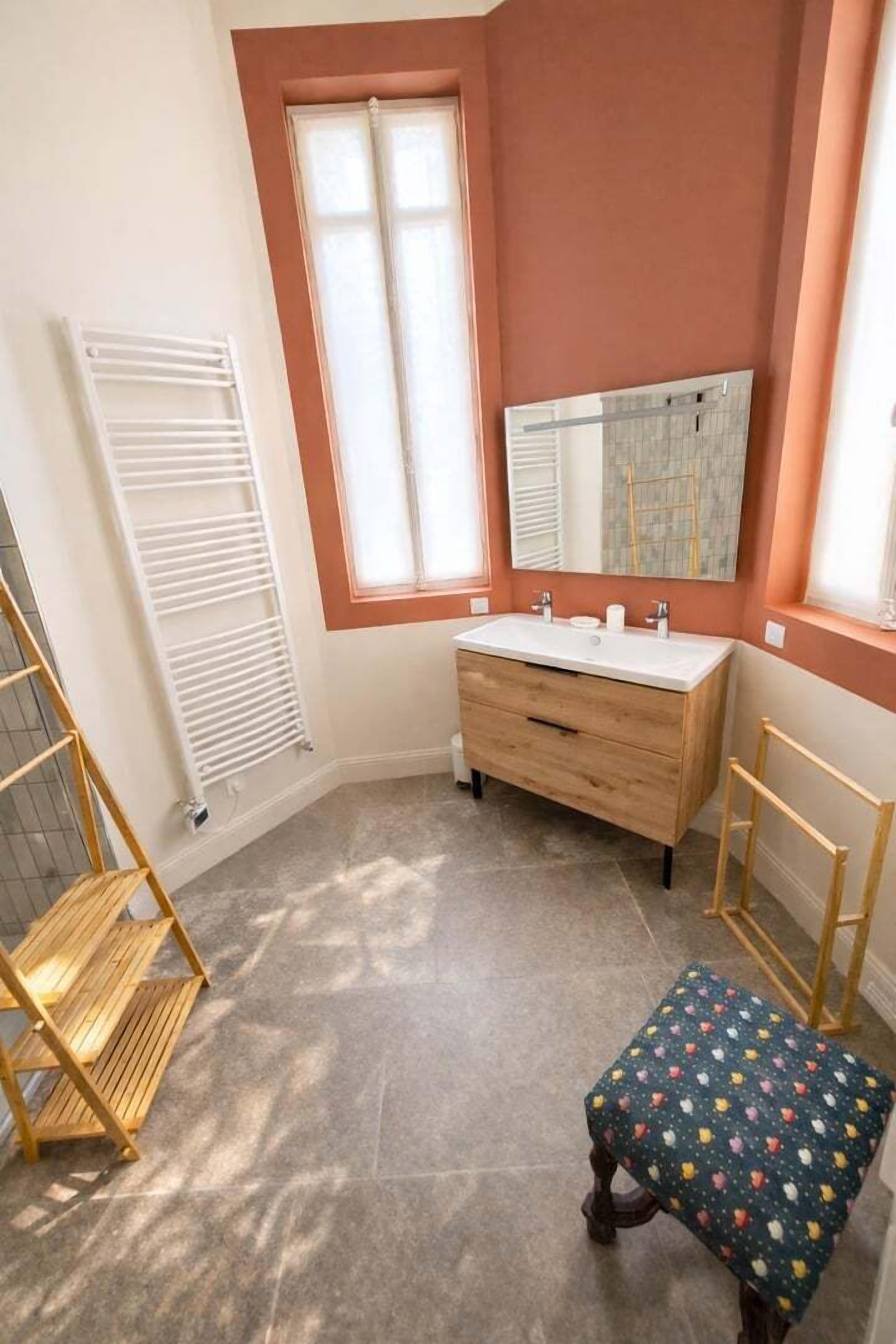 Un bagno con un mobile bagno in legno, uno specchio, una finestra e un termosifone.
