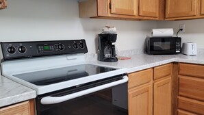 A kitchen with a stove, microwave, toaster, and coffee maker. - Top-Floor Duplex Near Marshall University (Huntington)