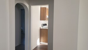 A hallway leading to a kitchen with wooden cabinets and a countertop. - Top-Floor Duplex Near Marshall University (Huntington)