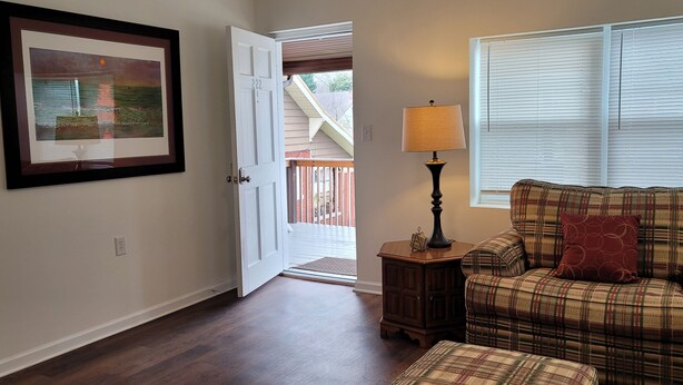 A living room with a plaid sofa, a lamp, a framed picture, and a door leading outside. - Top-Floor Duplex Near Marshall University (Huntington)