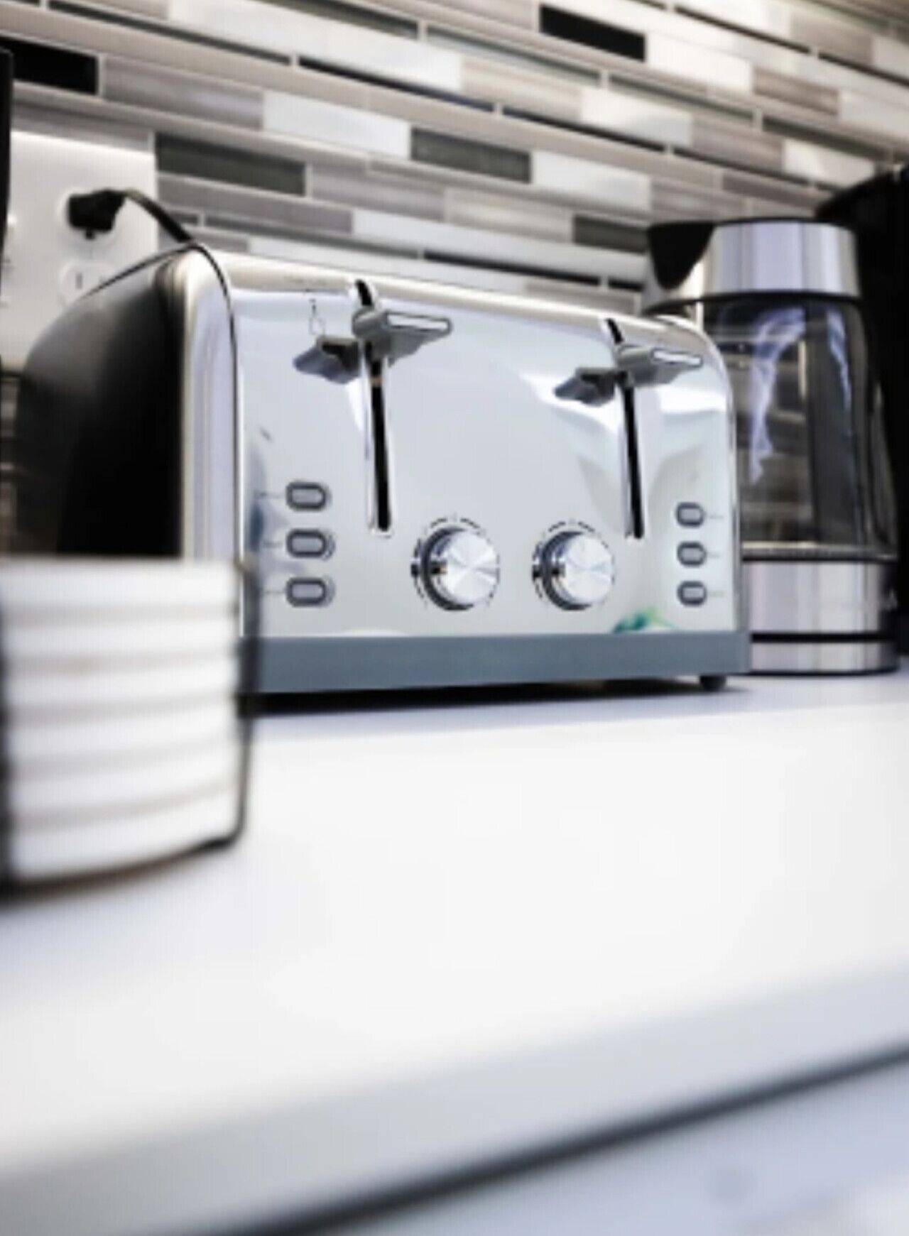 A modern kitchen with a stainless steel toaster and a coffee maker on the counter.