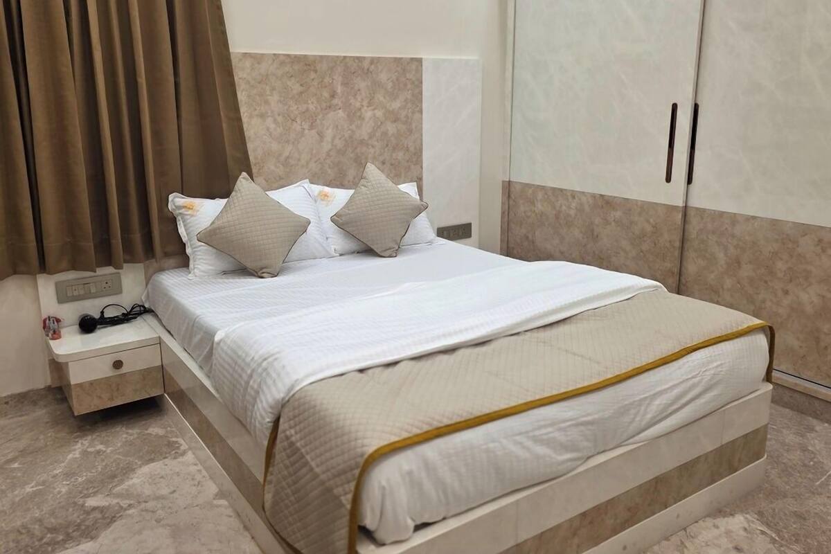Une chambre d’hôtel avec un lit, une table de chevet, une armoire et un rideau.