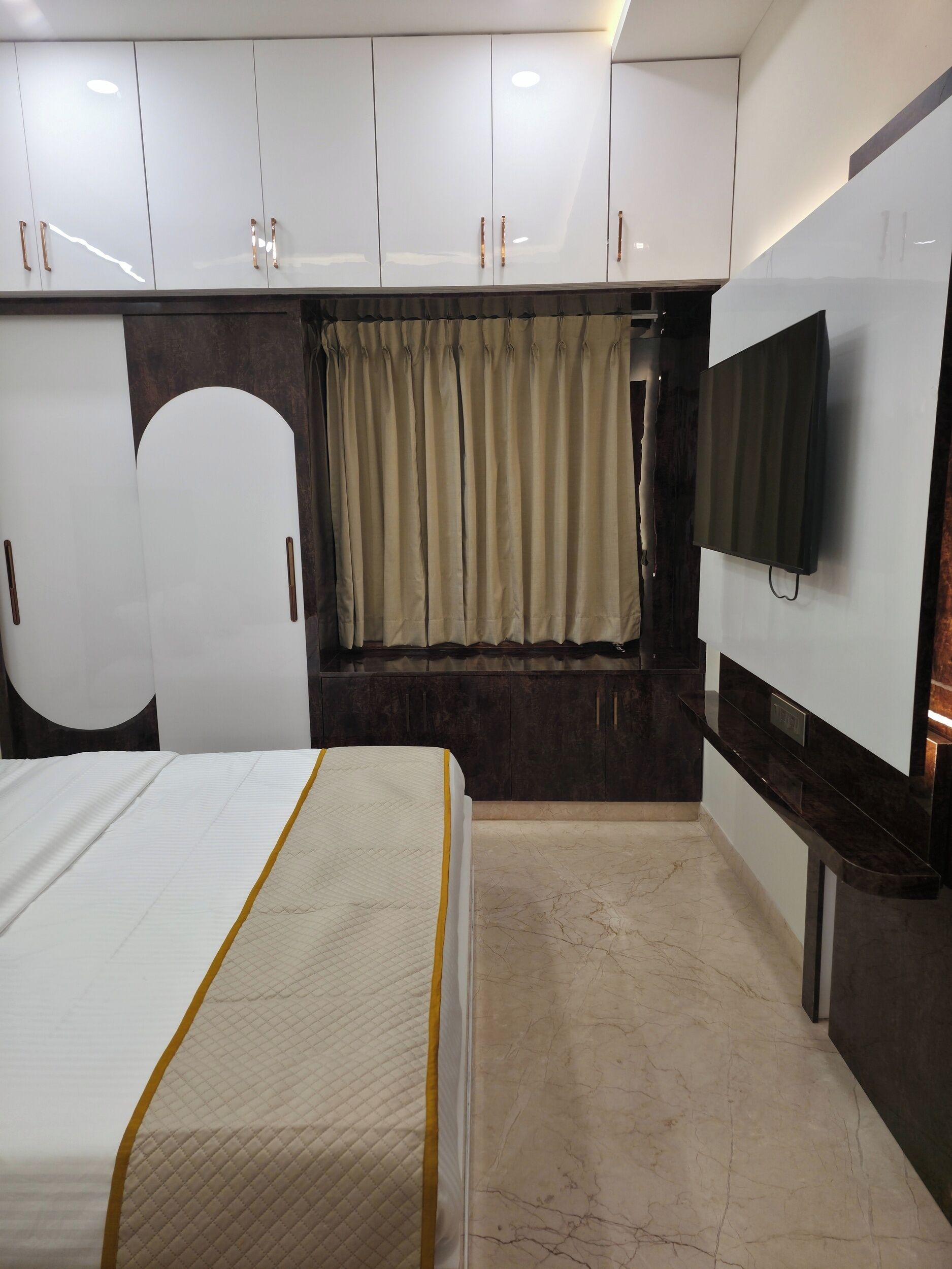 Une chambre d’hôtel équipée d’un lit, d’un téléviseur fixé au mur et d’une armoire avec un miroir.