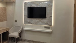 Un salon moderne avec un téléviseur à écran plat fixé sur un mur de marbre, une chaise blanche et une table en bois.