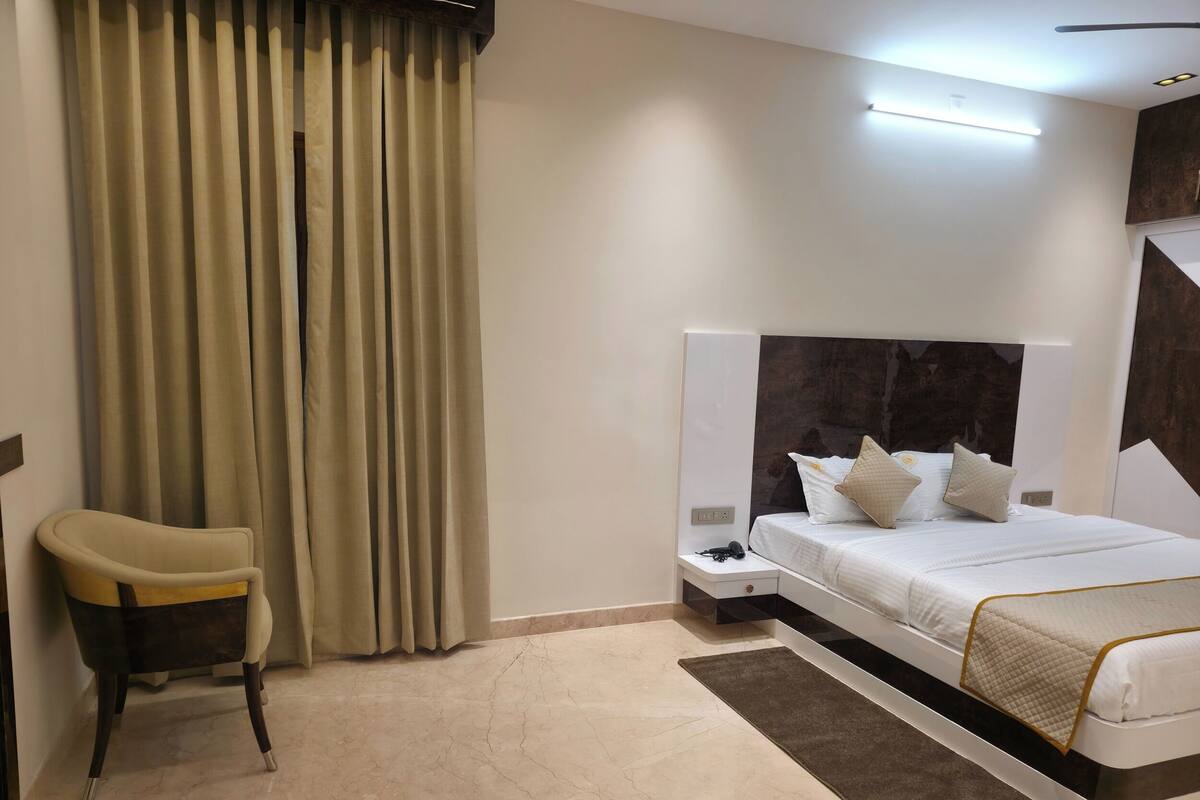 Une chambre d’hôtel moderne, équipée d’un lit, d’une chaise, d’une table de chevet et d’un rideau.