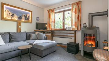 Ett modernt vardagsrum med en soffa, ett litet bord, en tv, en öppen spis och ett fönster med gardiner.