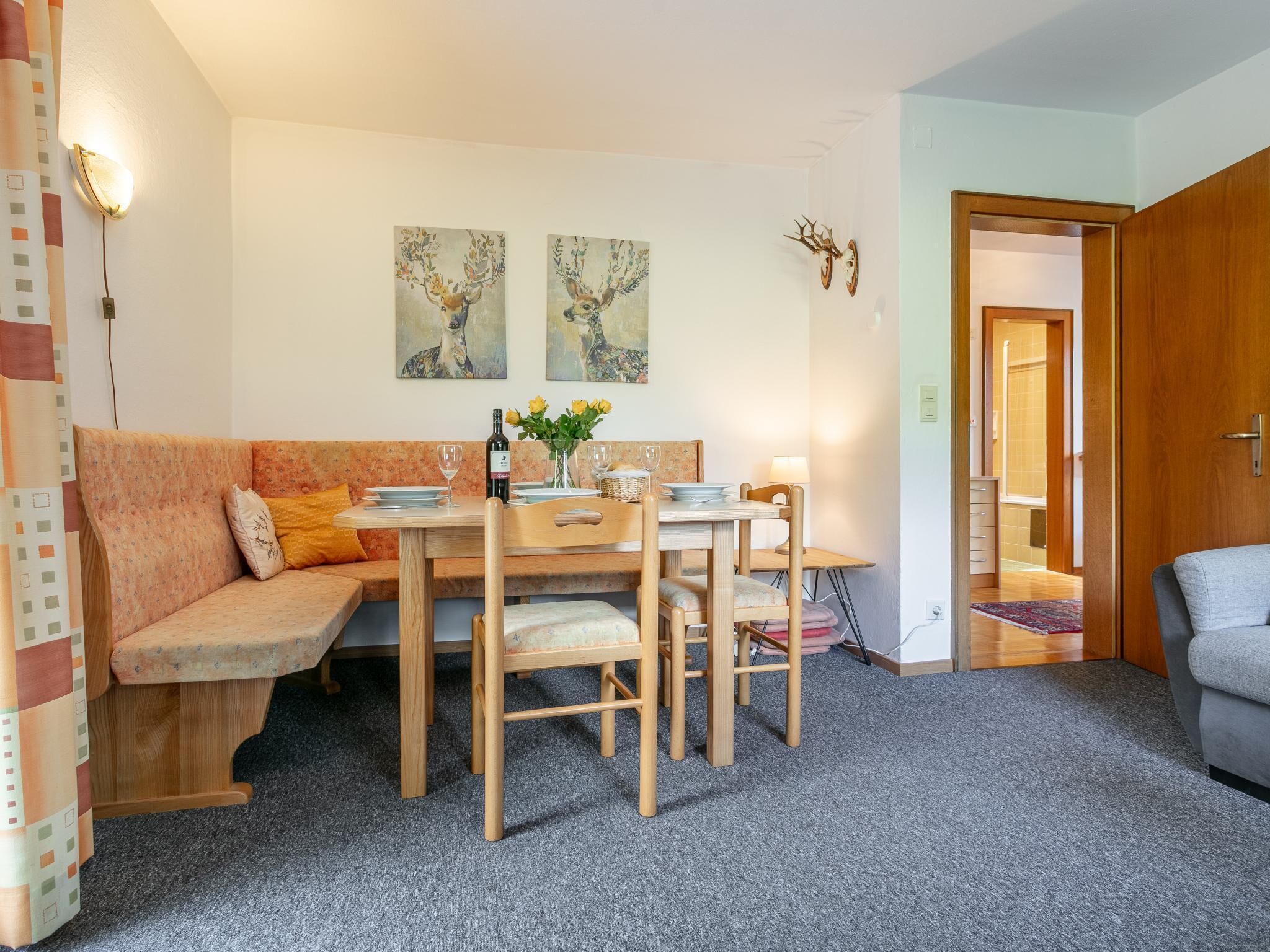 Un coin repas chaleureux avec une table et des chaises en bois, un canapé et deux tableaux représentant des cerfs, accrochés au mur.