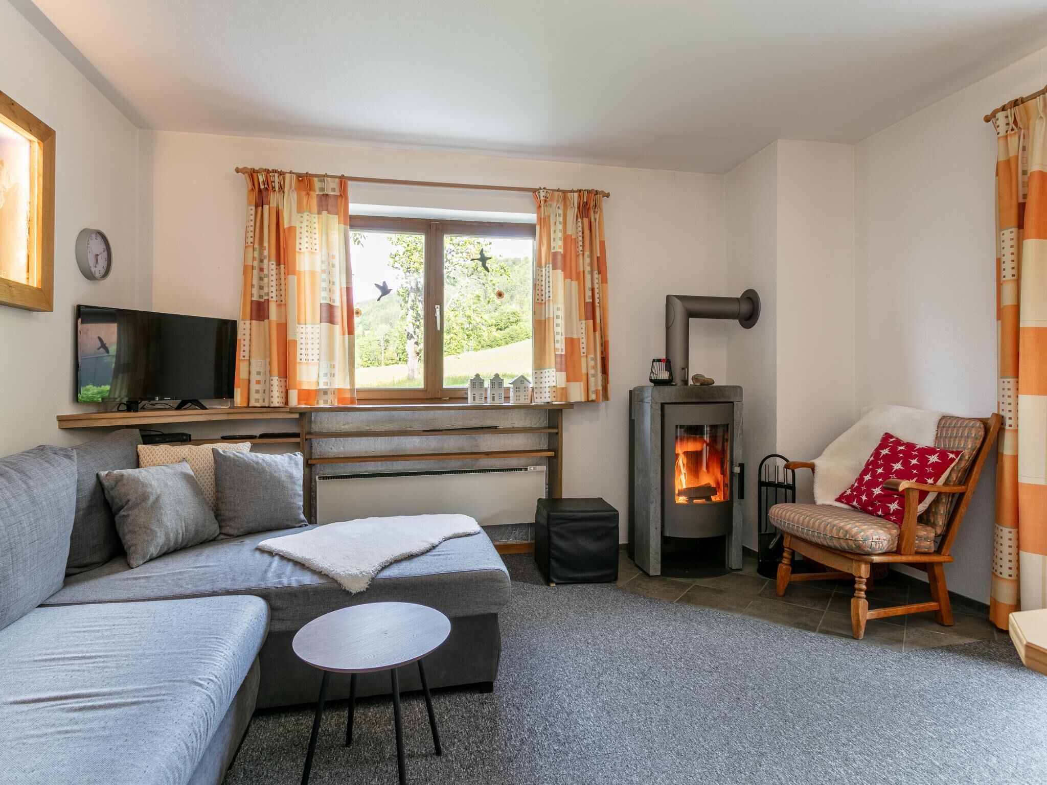 Una sala de estar con sofá, una mesita, televisor, chimenea y ventana con cortinas.