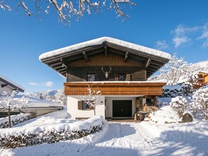 Un chalet moderne doté d’un toit en pente, d’un revêtement extérieur en bois et d’une tête de cerf fixée au mur.