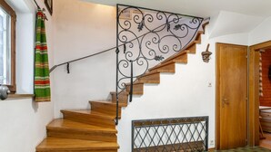 Uma escada de madeira com corrimão de metal, um tapete estampado e uma porta de madeira.