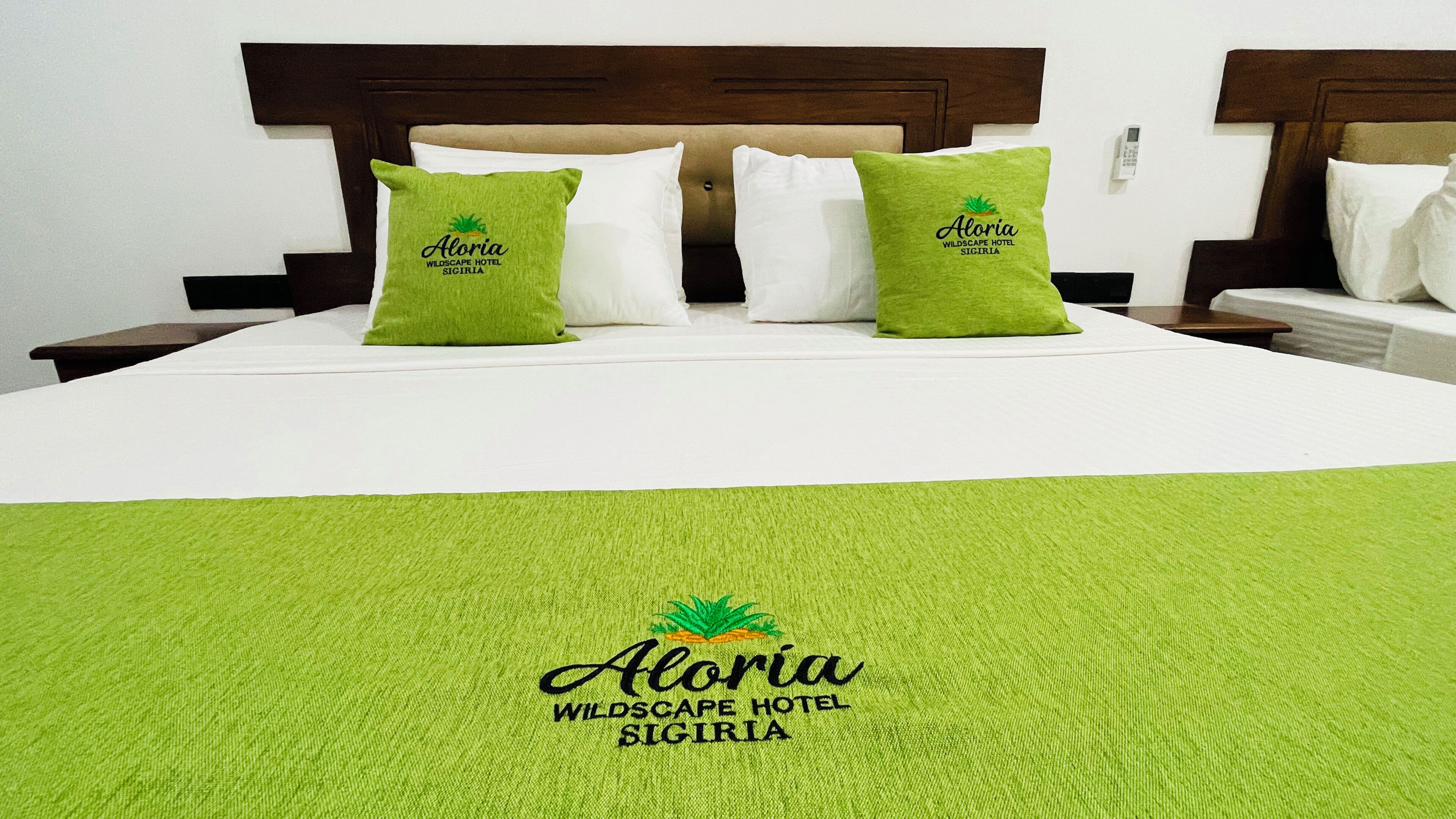 A bed with two green pillows, a white bedspread, and a green throw blanket.