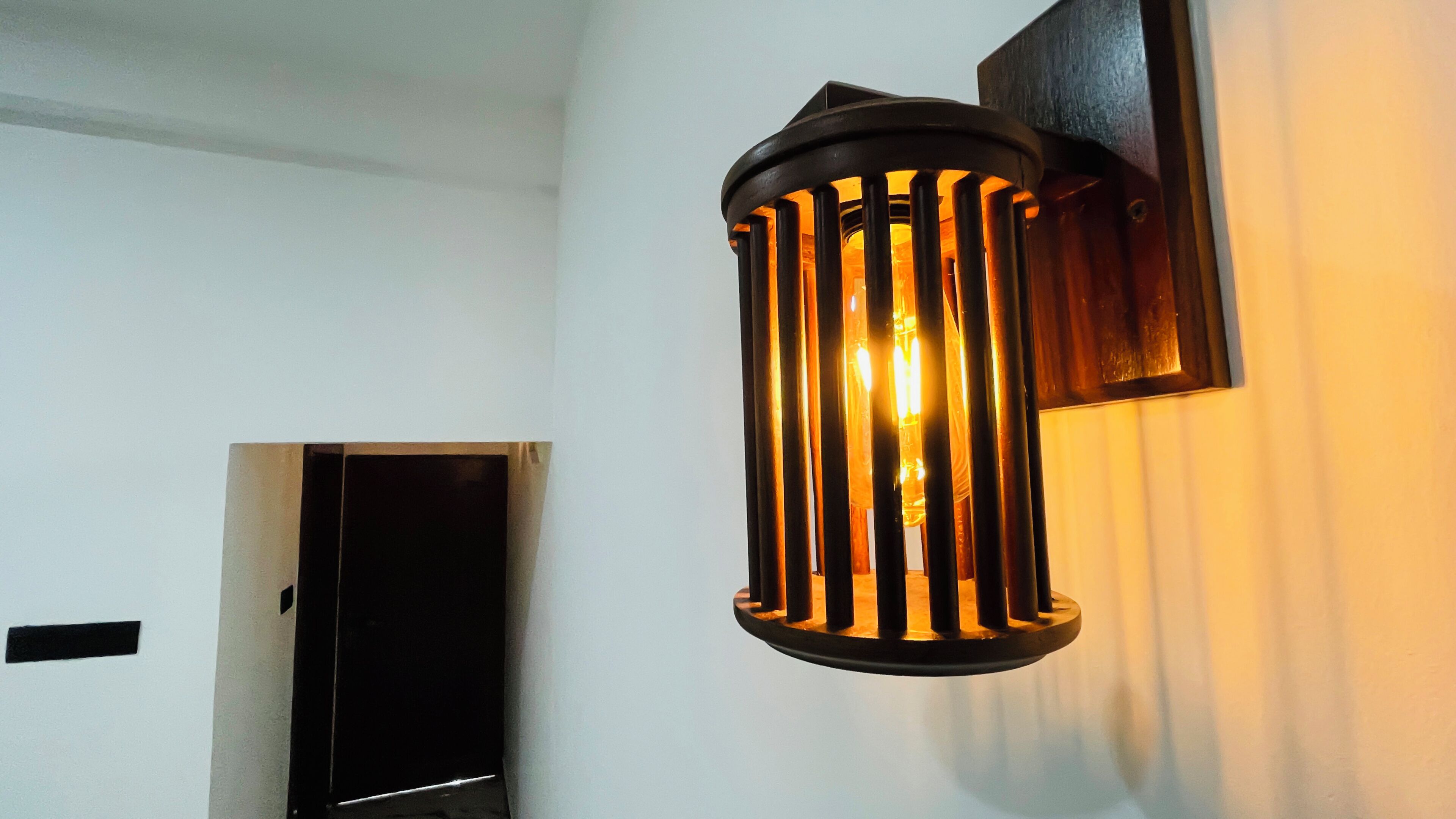 A wall-mounted light fixture with vertical bars and a cylindrical shape.