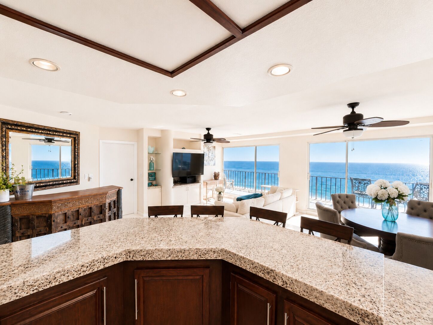 A kitchen with a granite countertop, wooden cabinets, and a large window overlooking the ocean.