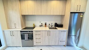 Una cocina moderna con armarios de madera clara, electrodomésticos de acero inoxidable y piso de mármol.