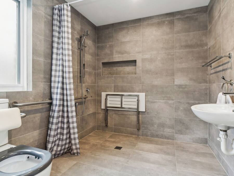 Et moderne badeværelse med bruser, toilet og håndvask.