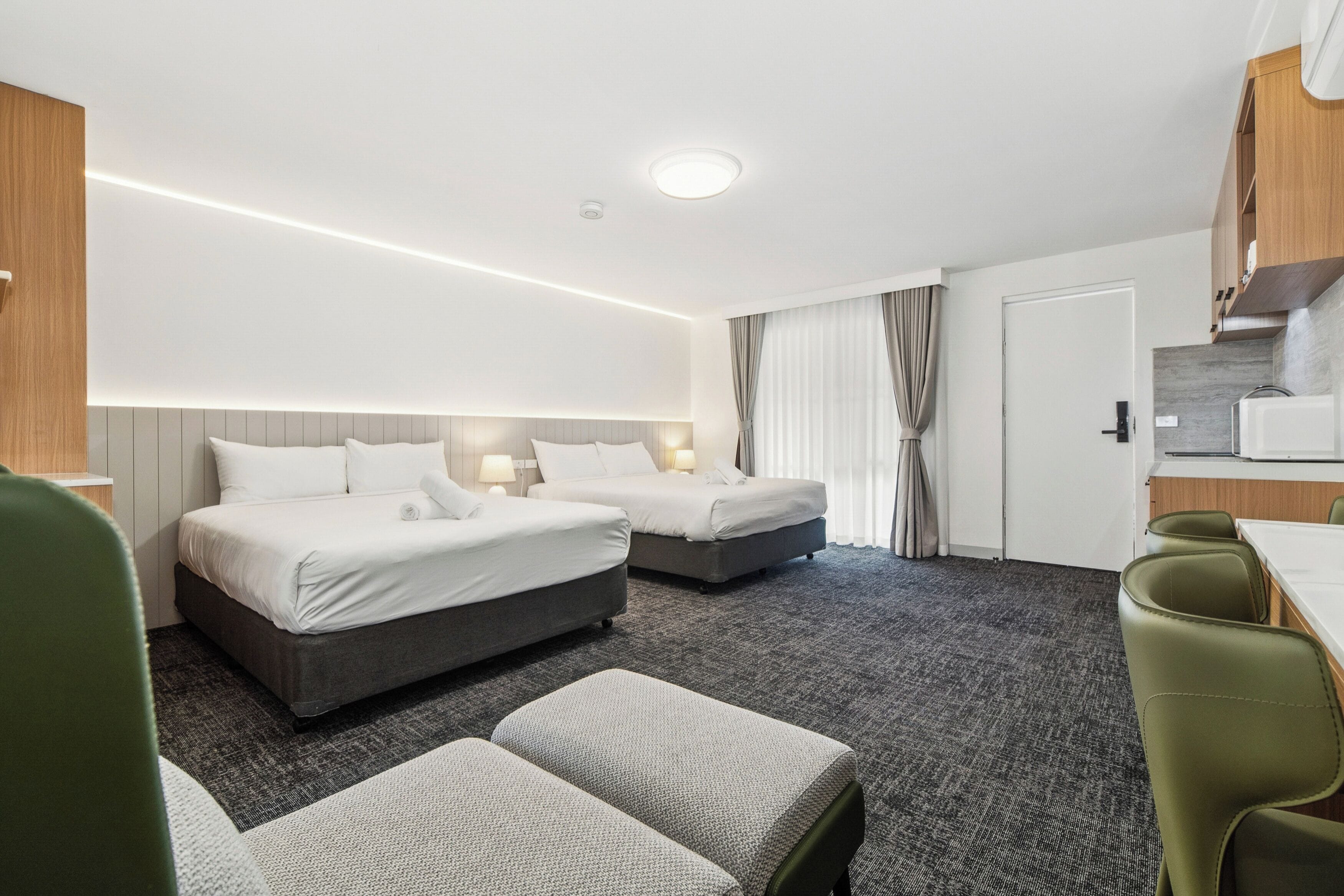 A hotel room with two beds, a kitchenette, a dining area, and a separate seating area.