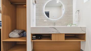 A modern bathroom with a wooden vanity, a round mirror, and a marble countertop.