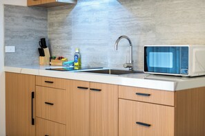 A modern kitchen with a built-in microwave, a sink, and wooden cabinets. - Frankston Bay Motel (Melbourne)