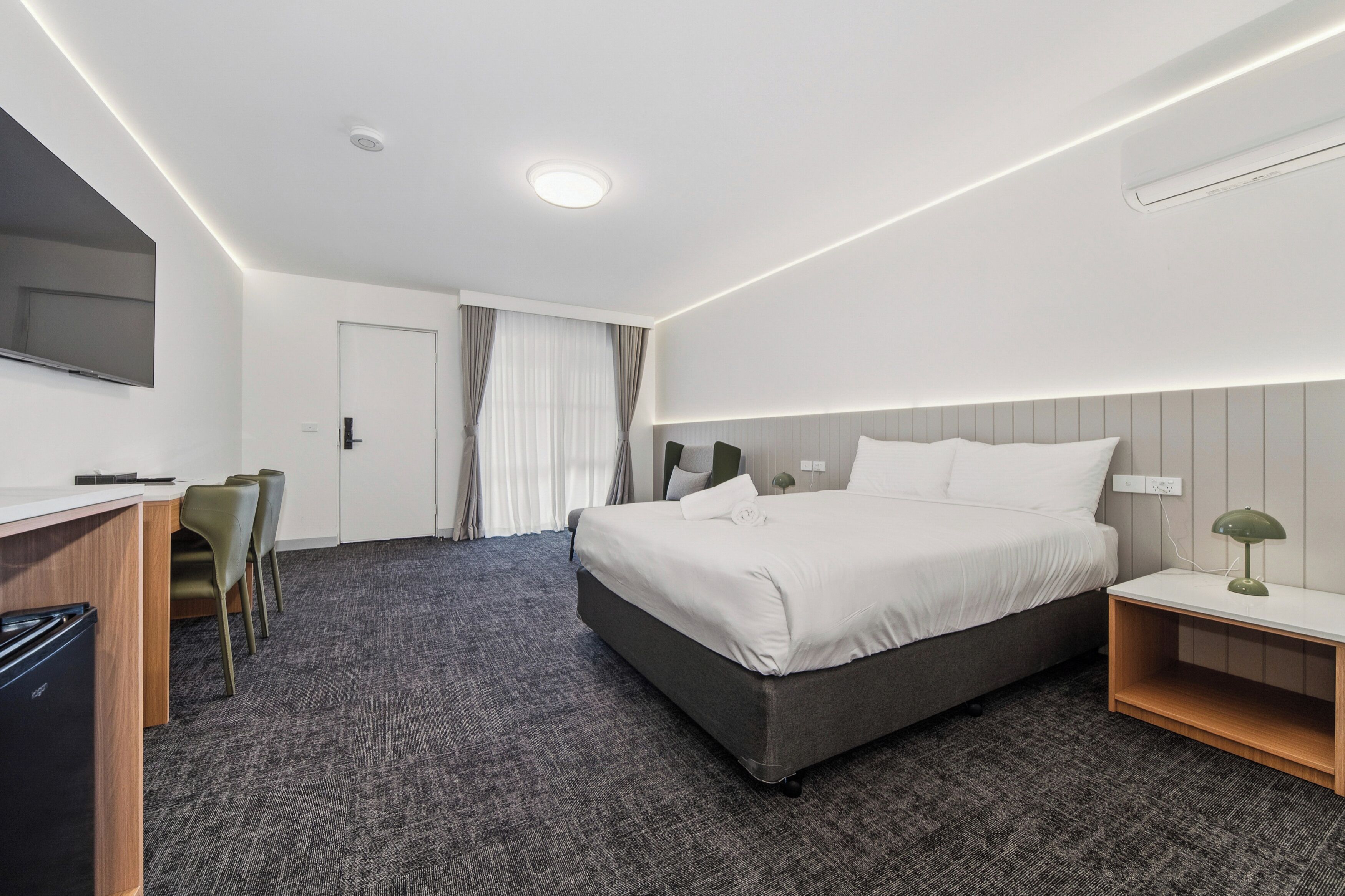 Una habitación de hotel con cama, escritorio, sillas y televisor.