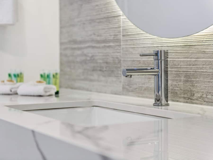 Un baño moderno con un grifo cromado, un lavabo blanco y un espejo grande.