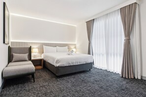 A hotel room with a bed, a chair, a nightstand, and a large window with curtains. - Frankston Bay Motel (Melbourne)
