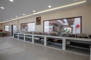 Disposição de buffet com várias estações de serviço, uma janela grande e teto com iluminação embutida.