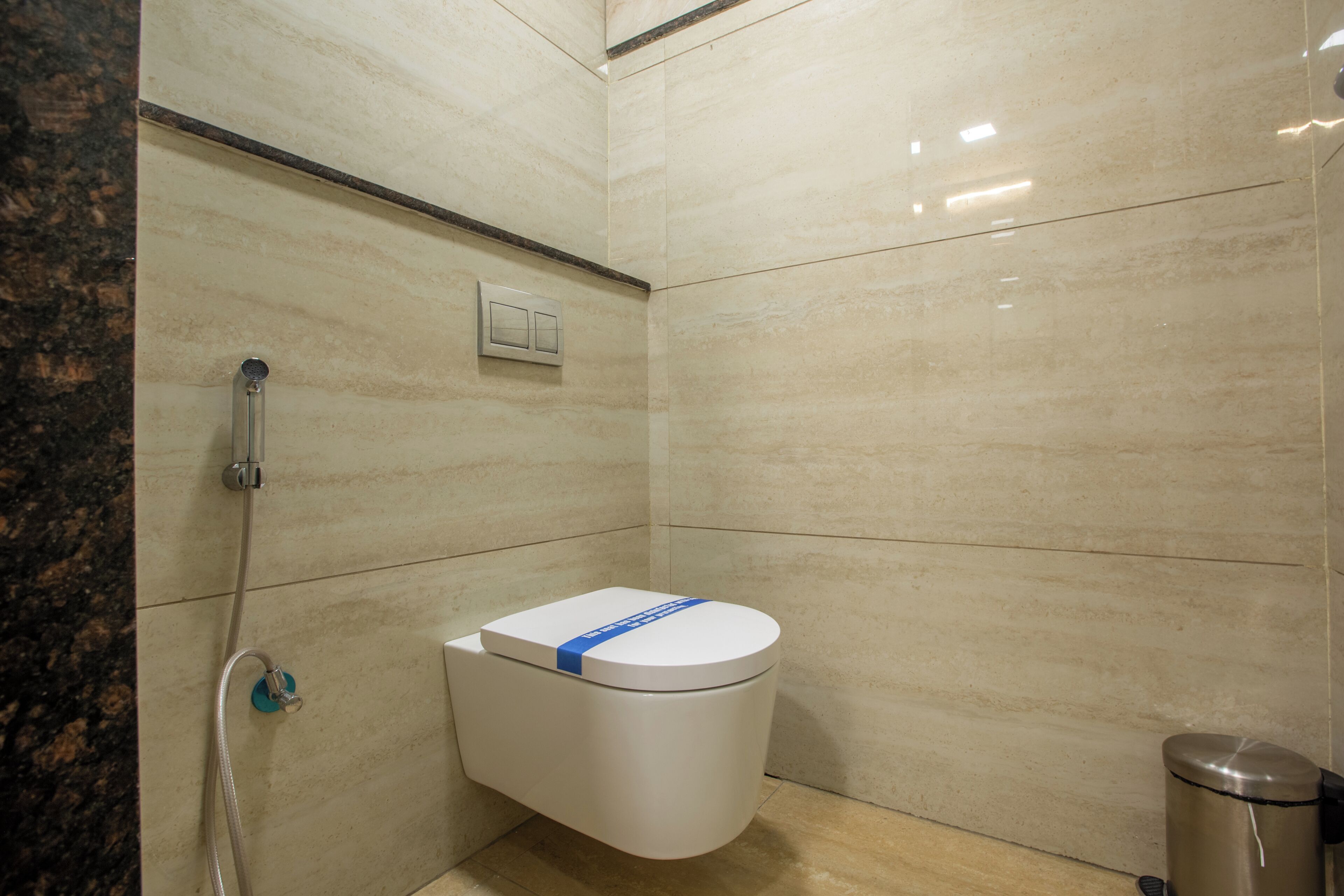 A bathroom with a toilet, a shower, and a trash bin.