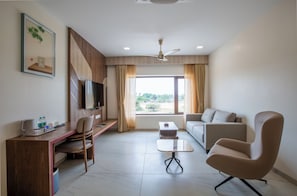 A modern room with a desk, chair, sofa, and a ceiling fan.