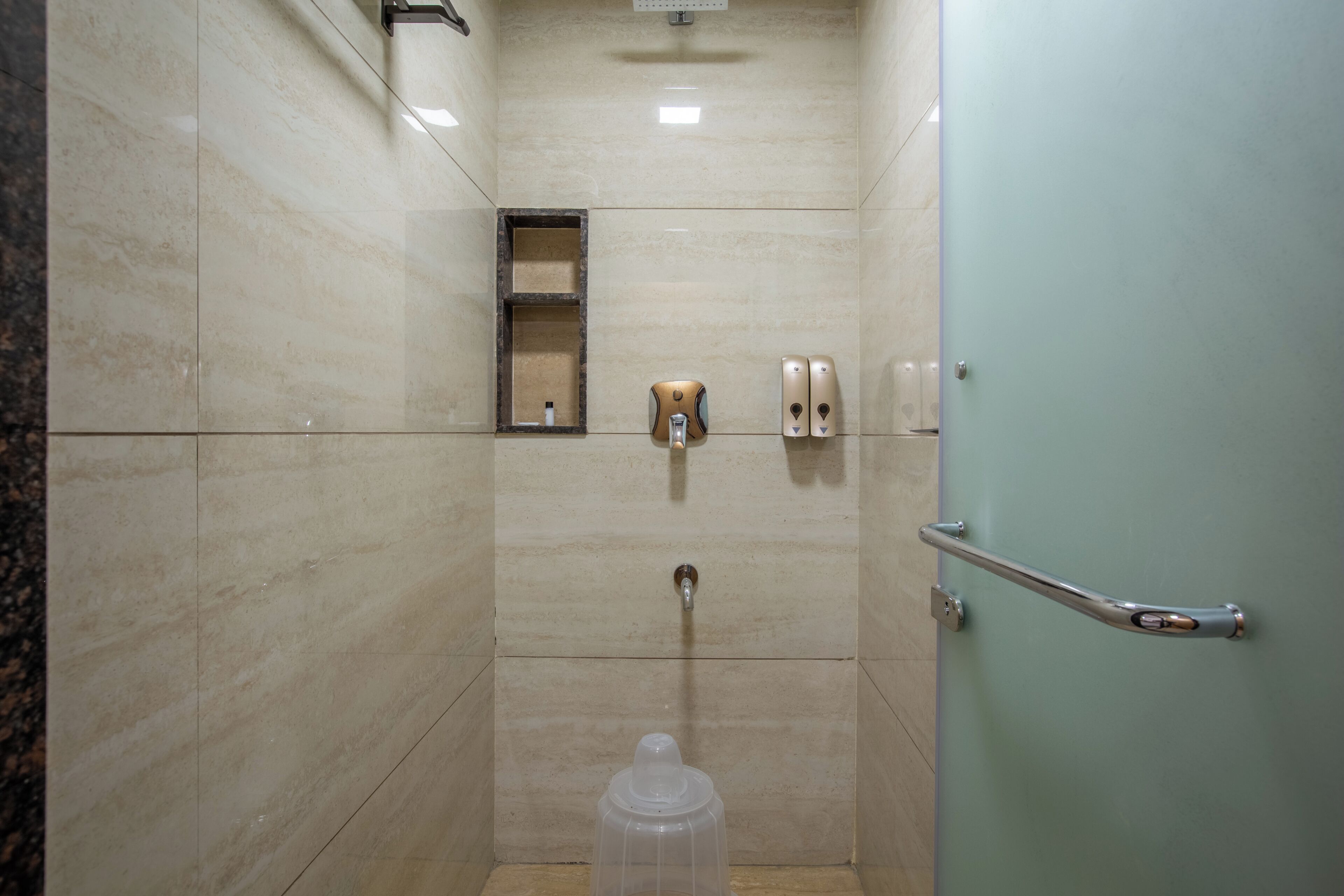 Un baño con ducha, inodoro, secador de manos y dispensador de jabón.