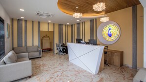 Un espace d’accueil moderne, doté d’un canapé, d’un bureau et d’une décoration murale sur le thème du paon.
