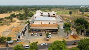 A two-story building with a flat roof, a signboard, and a parking area with cars. - La Antaraa  (Tiruchendur)