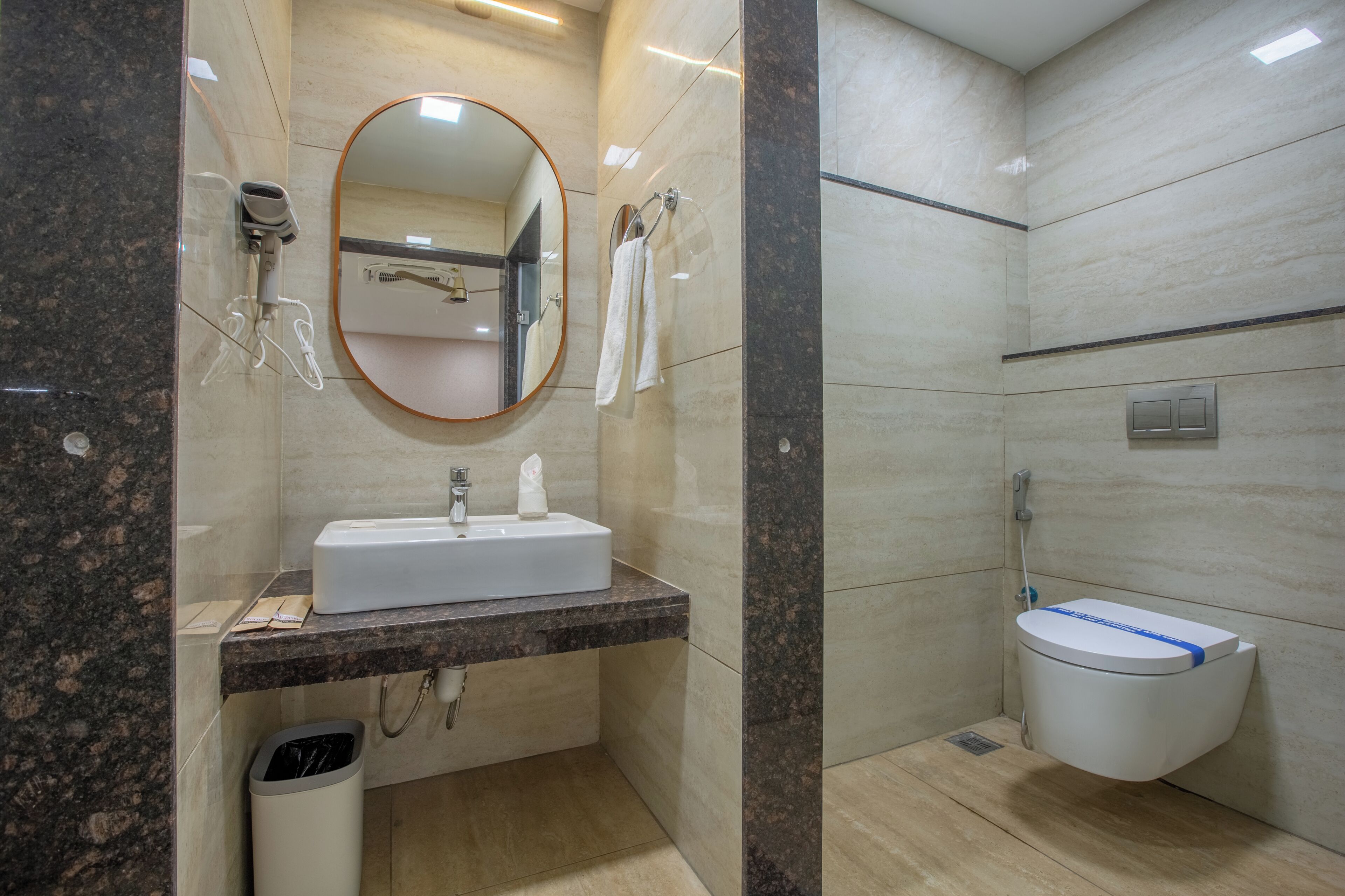 Une salle de bain moderne équipée d’un lavabo, d’un miroir, d’un porte-serviettes et de toilettes.