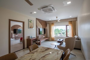 A modern hotel room with a dining area, a TV, a sofa, and a large window. - La Antaraa  (Tiruchendur)