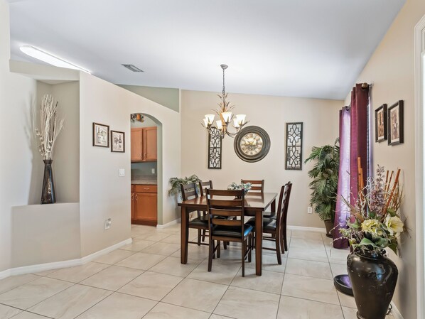 A dining area with a chandelier, a clock, and framed artwork on the walls. - Ocala 3BR Home + Perfect for WEC & Silver Springs (Ocala)