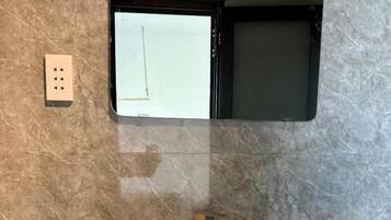 Une salle de bain dotée d’un grand lavabo rond, d’un miroir fixé au mur et d’une prise de courant.