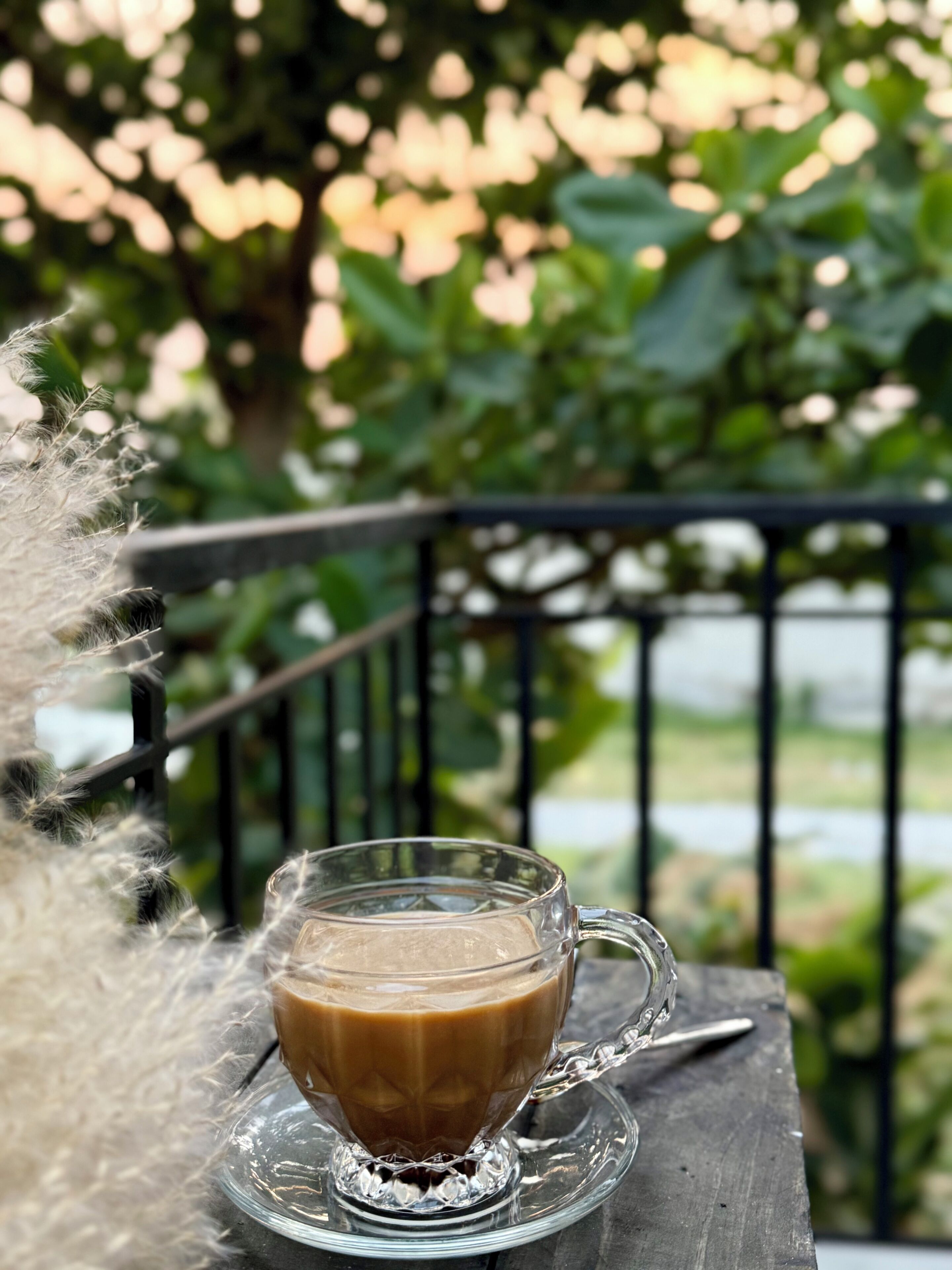 Une tasse de café en verre posée sur une soucoupe en verre transparent, sur une table en bois.