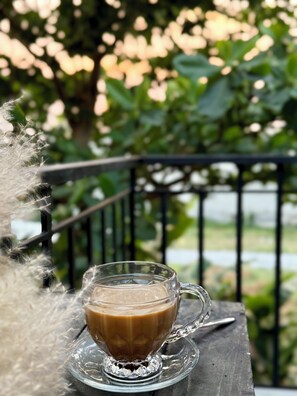 Une tasse de café en verre posée sur une soucoupe en verre transparent, sur une table en bois.